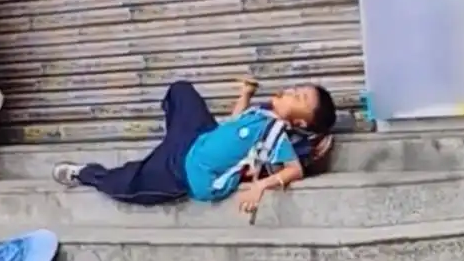妈妈忘接孩子 男孩淡定躺台阶吃东西